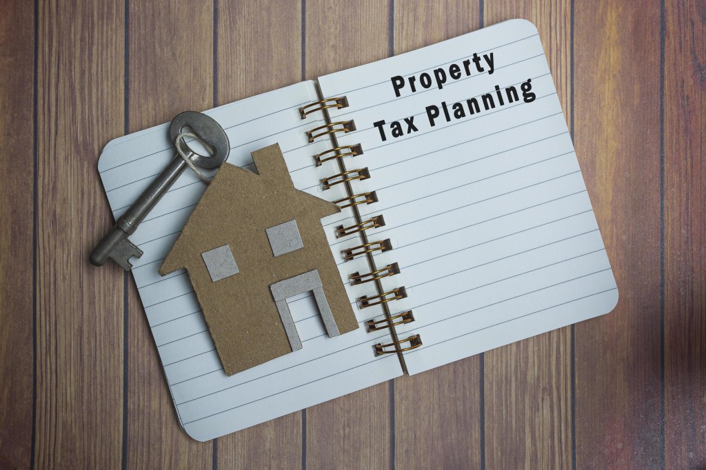 Picture of: Property tax planning text on a note book with house model and key